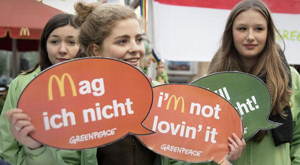 Junge Aktivistinnen protestieren mit Sprechblasen gegen McDonald's