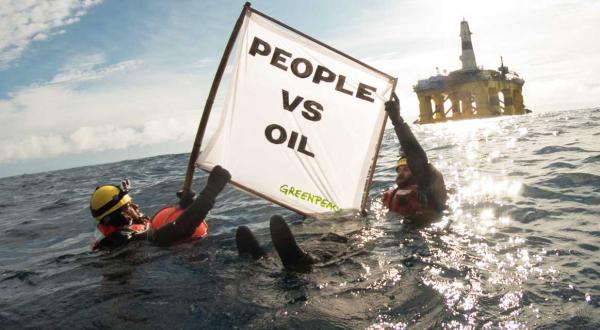 Zwei Schwimmer im Pazifik protestieren mit einem Banner vor der Polar Pioneer