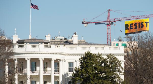 Das Weiße Haus in Washington, darüber ein Greenpeace-Banner mit der Aufschrift "Resist"