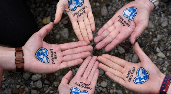 Fünf Hände mit "Planet Earth First" Wasser-Tattoos