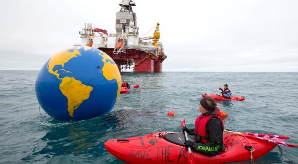Aktivist im Kanu mit Erdkugel vor Ölplattform Songa Enabler