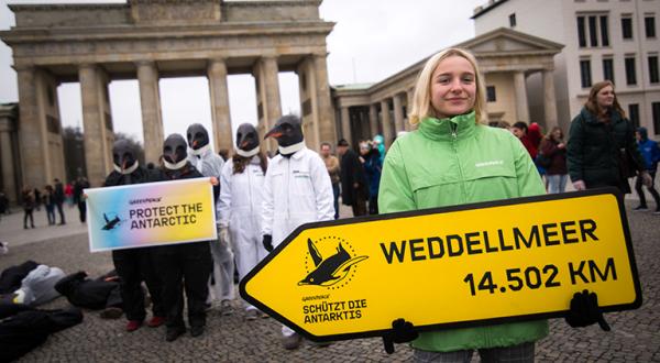 Greenpeace-Aktivistin mit Wegweiser vorm Brandenburger Tor