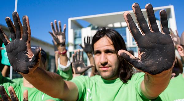 Greenpeace-Aktivisten mit schwarzen Händen demonstrieren vorm Bundeskanzleramt für den Kohleausstieg