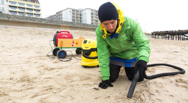 Greenpeace-Aktivist mit Staubsauger am Strand von Borkum