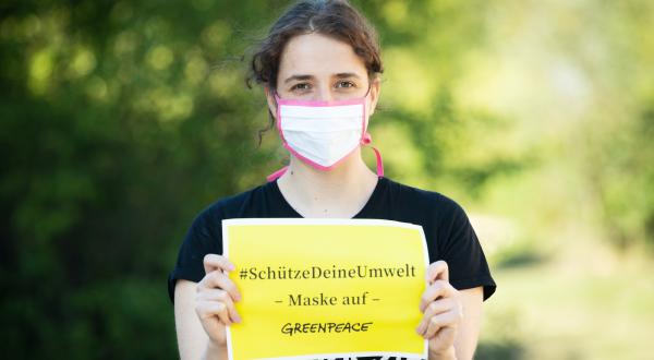 Greenpeade-Mitarbeiterin mit Stoffmaske