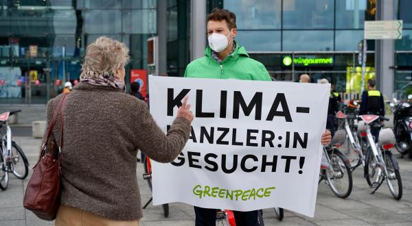 Greenpeace-Aktivist mit Banner "Klimakanzler:in gesucht"