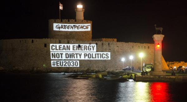 Eine Projektion mit dem Text "Clean Energy not dirty politics" ist bei Nacht an die Mauern der Burg Rhodos projiziert