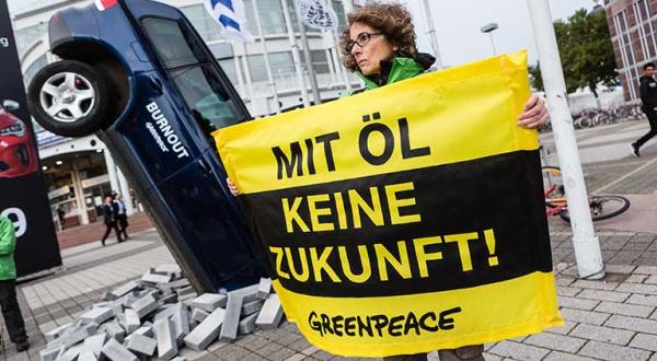 Mit einem schräg im Boden steckenden VW-Auto mit qualmendem Auspuff demonstrieren Greenpeace-Aktivisten vor der Internationalen Automobilausstellung (IAA) in Frankfurt gegen die Modellpolitik der Autoindustrie.