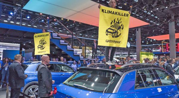 Greenpeace-Aktivisten mit Banner "Klimakiller" auf SUV auf IAA