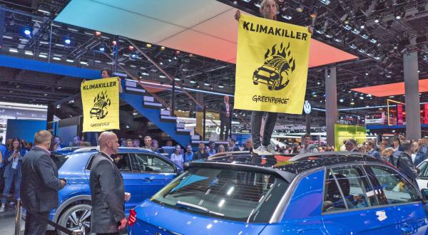 Greenpeace-Aktivisten mit Banner "Klimakiller" auf SUV auf IAA