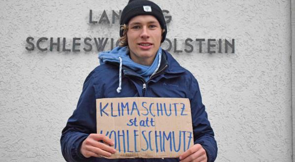 Jakob Blasel mit Schild "Klimaschutz statt Kohleschmutz" vor Landtag in Kiel