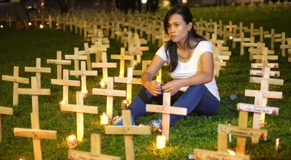 Taifun-Überlebende Joanna Sustento sitzt in einem Meer aus Kreuzen