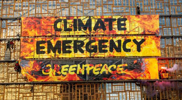 Flammenbanner mit "Climate Crisis" an Fassade von EU-Gebäude in Brüssel