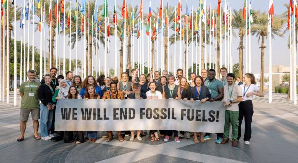 Greenpeace-Delegation bei der COP28 mit Banner "we will end fossil fuels"