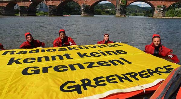 Greenpeace-Schwimmer in der Mosel fordern, die  AKW Cattenom und Fessenheim abzuschalten. Sie halten ein Banner: "Radioaktivität kennt keine Grenzen!" August, 2013 