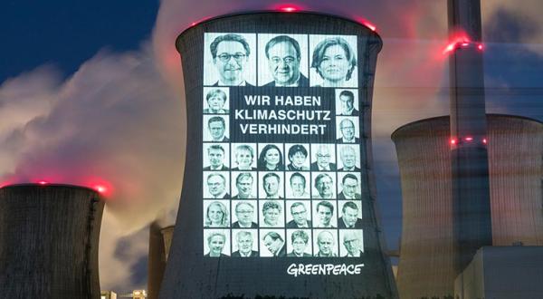 Projektion auf Kühlturm des Braunkohlekraftwerks Neurath: 31 Portraits der schlimmsten Klimabremser aus Union und SPD sowie den Schriftzug "Wir haben Klimaschutz verhindert".