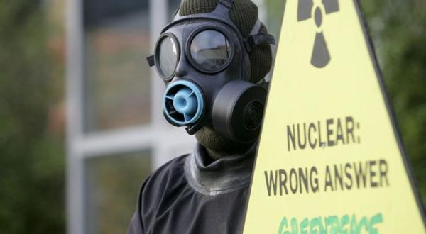 Greenpeace-Aktivist mit Gasmaske und Protestschild "Nuclear Power: Wrong Answer"
