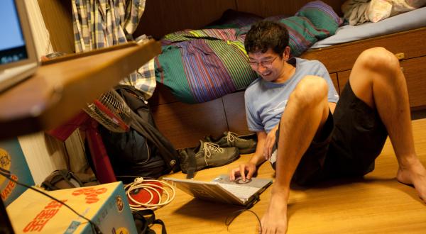 Daisuke Miyachi von Greenpeace Japan sitzt auf dem Boden eines Zimmers - vor sich ein Laptop.