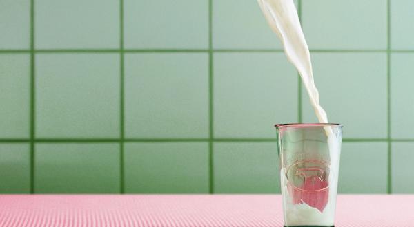 Milch fließt in ein Glas.