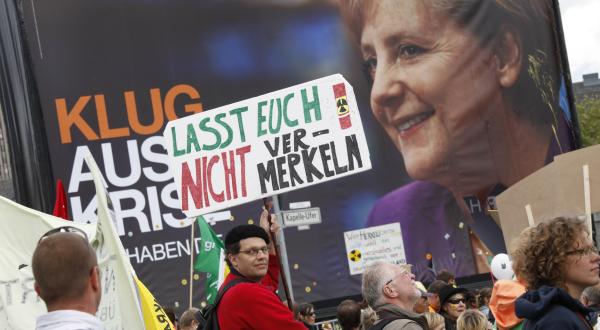Demonstration in Berlin gegen die geplante Laufzeitverlängerung von Atomkraftwerken. Im Hintergrund ein Wahlkampfplakat von Merkel, 2009.