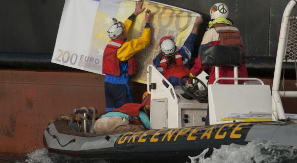 Greenpeace-Aktivisten befestigen falsche Banknoten an dem Trawler Maartje Theadora. Die Fanglizenzen für solche Schiffe werden zu 90 % aus EU-Steuergeldern finanziert.