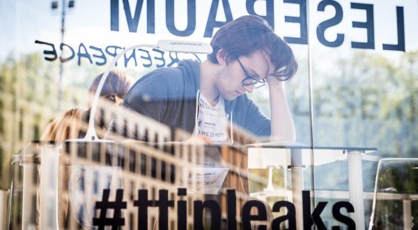 Junger Mann liest im gläsernen Leseraum TTIP-Dokumente