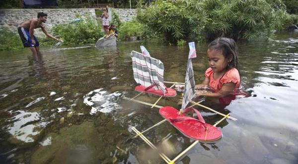 philippinisches Mädchen spielt mit selbst gebastelten Boot im Juni 2011