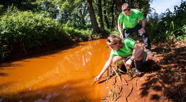 Greenpeace-Aktivisten nehmen Proben von verockertem Spreewasser.