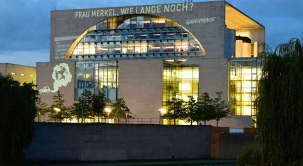 Projektion an das Bundeskanzleramt: „Frau Merkel, wie lange noch?“ und eine in Autoabgase gehüllte Erdkugel