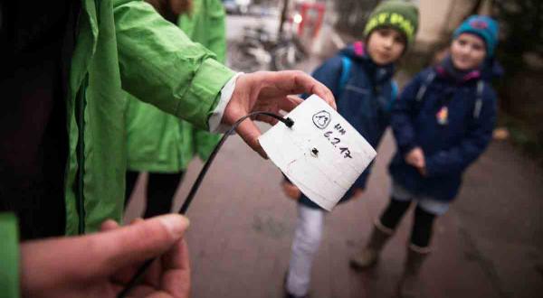 Schulkinder betrachten Messvorrichtung von Greenpeace. Damit wird die Stickoxidbelastung nahe einer Berliner Schule ermittelt.