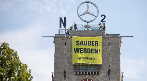 Auf dem Uhrturm des Stuttgarter Hauptbahnhofs machten Greenpeace-Aktivisten aus dem Mercedes-Stern ein NO2-Zeichen; auf ihrem Banner steht "Sauber werden!".