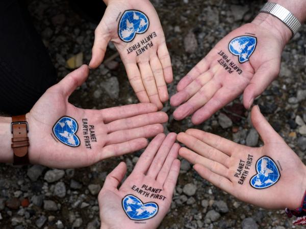 Offene Handflächen mit „Plan Earth First“ Tattoo die nach oben zeigen