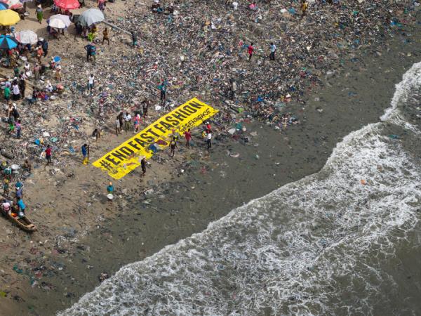 Fast Fashion und Abfallkolonialismus – ein Greenpeace-Banner am Strand in Ghana mit der Aufschrift "END FAST FASHION"