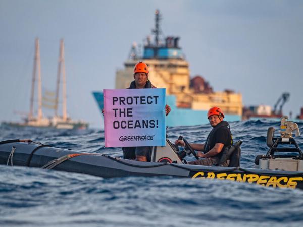 Protest gegen Tiefseebergbau im Pazifik Victor Pickering, ein Aktivist von Greenpeace-International aus Fidschi, zeigt ein Banner mit der Aufschrift "Protect the Oceans" (Schützt die Ozeane) vor der Maersk Launcher. Das Schiff wurde von DeepGreen gechartert, einem der Unternehmen, die die Ausbeutung des kaum verstandenen Ökosystems der Tiefsee vorantreiben. Die Rainbow Warrior befindet sich in der Clarion Clipperton Zone im Pazifik, um Zeugnis von der Tiefseebergbauindustrie abzulegen. 
