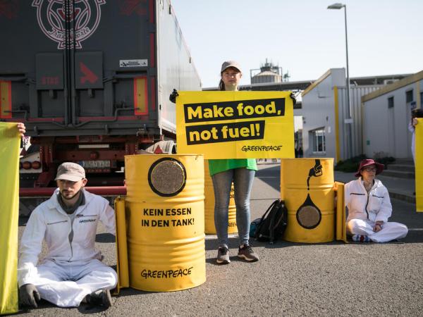 Greenpeace Aktivist:innen protestieren gegen Biokraftstoff am Eingang der Ethanolanlage von Crop Energies in Zeitz. Ihre Forderung "Kein Essen in den Tank" steht auf englisch auf einem Banner.