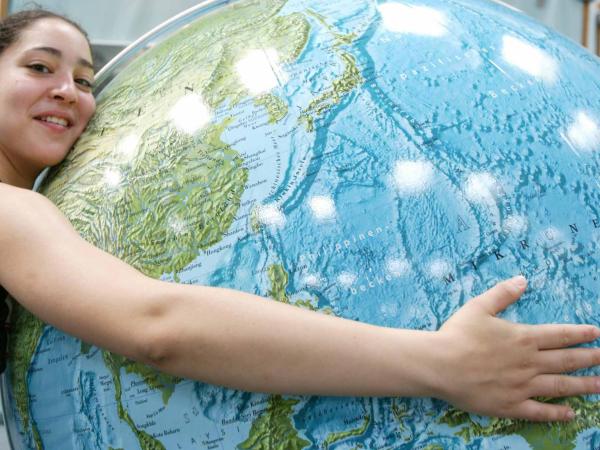 Eine junge Frau umarmt die Erdkugel - einen Globus