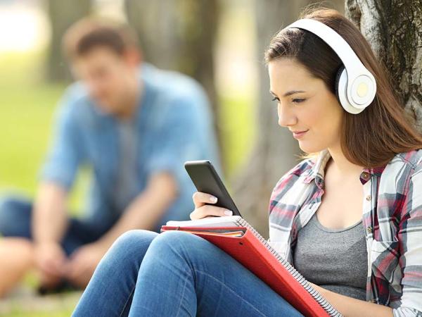 Frau auf einer Wiese mit Kopfhörer und Smartphone