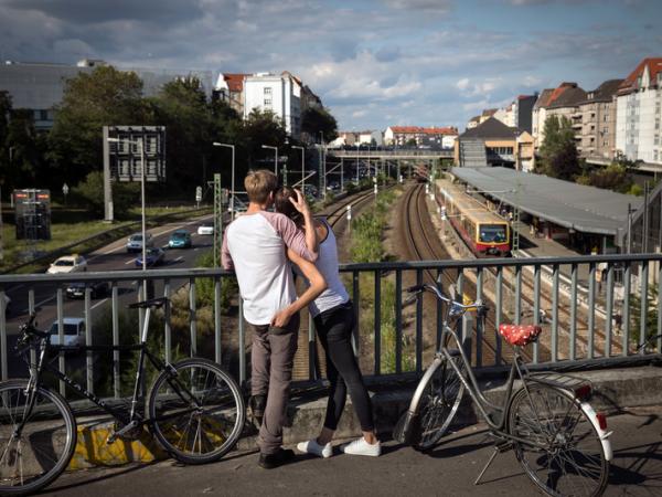 Junger Mann und junge Frau auf Brücke schauen auf den Verkehr unter ihnen