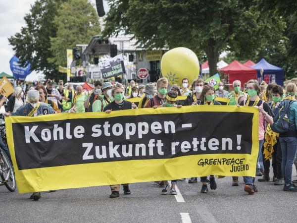 Jugendliche protestieren auf einer Demo. Sie tragen ein Frontbanner mit der Aufschrift: Kohle stoppen Zukunft retten, Greenpeace Jugend