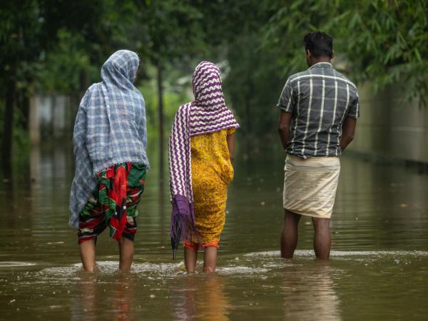 Menschen in Bangladesch gehen durch eine überschwemmte Straße
