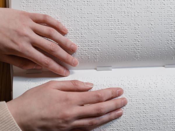Zwei Hände, die Blindenschrift (Braille) ertasten 